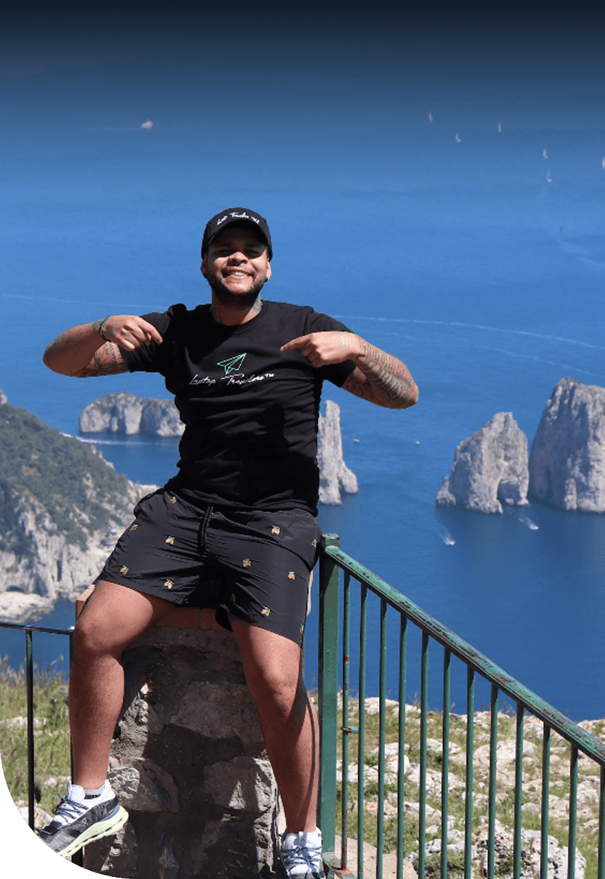 A man sitting on top of a railing near the ocean.