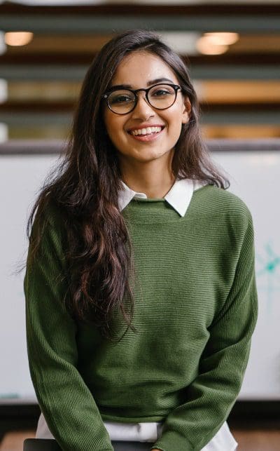 A woman with glasses and long hair wearing a green sweater.