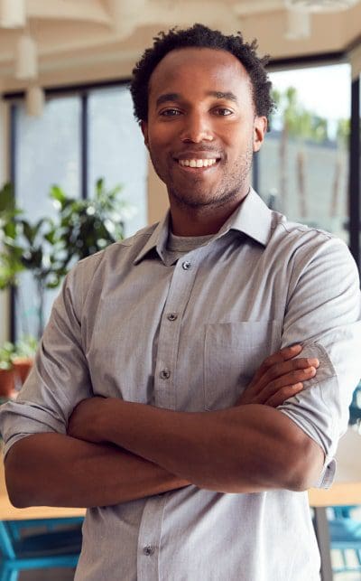 A man with his arms crossed wearing a gray shirt.